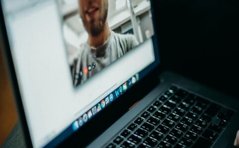 Laptop zeigt einen Mann als "Talking Head" in einem Zoom Online-Meeting