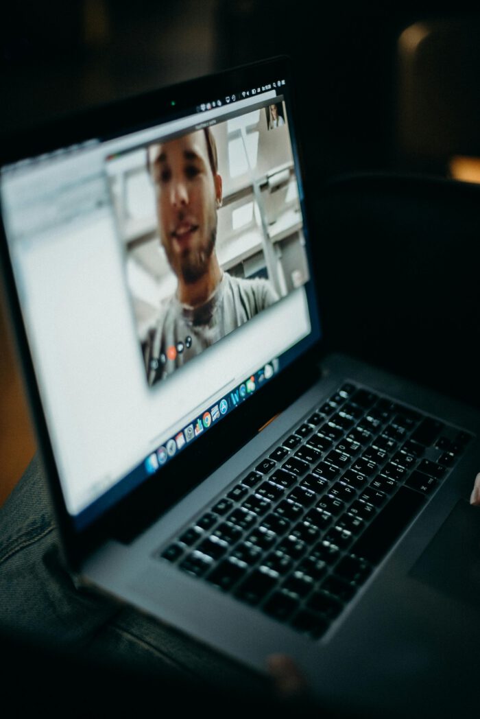 Laptop zeigt einen Mann als "Talking Head" in einem Zoom Online-Meeting